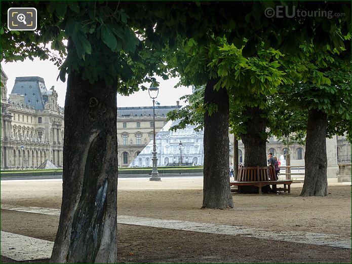 View East through trees in Tuileries Gardens to pyramid of The Louvre