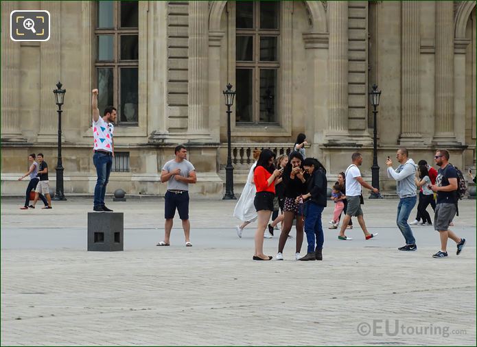 Tourists taking pictures on platform in Cour Napoleon