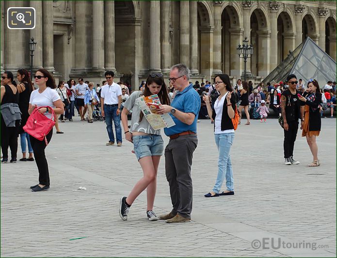 Tourists map reading in Cour Napoleon of The Louvre